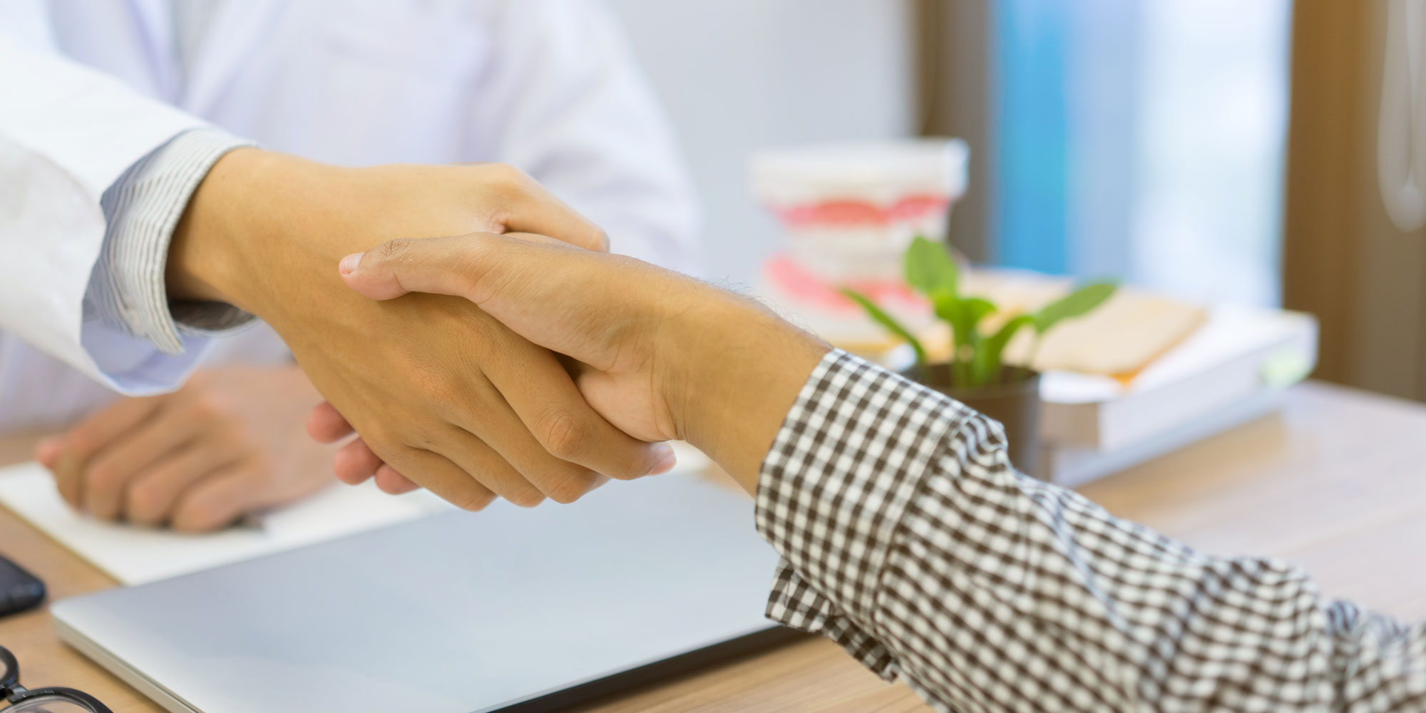 dentist shaking hand over desk